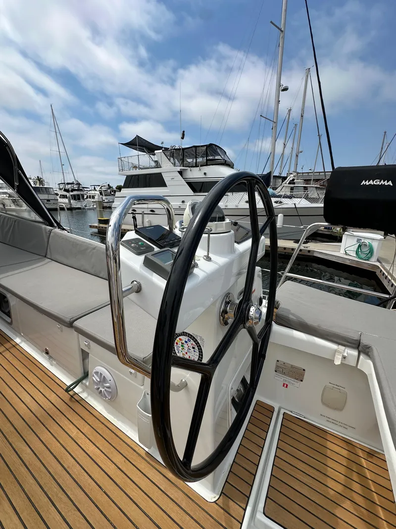 Slide: The Image of Steering wheel of a 2018 Jeanneau 54 yacht docked at a marina under blue skies. - 34