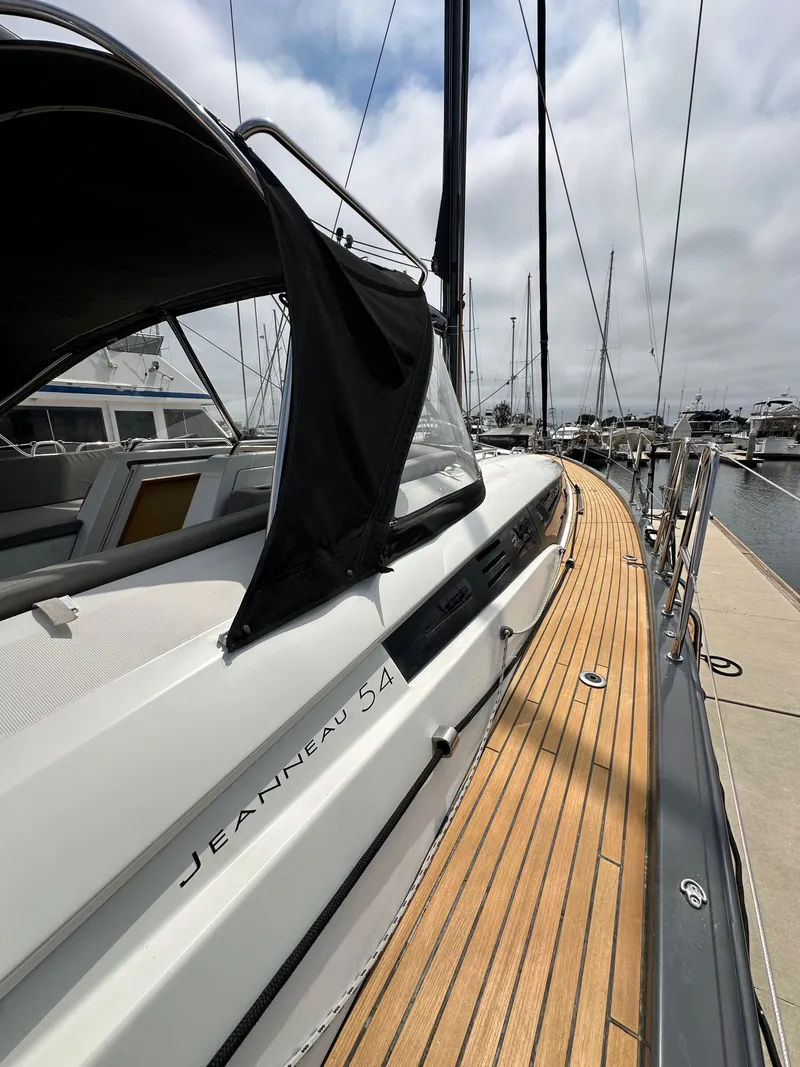 Slide: The Image of 2018 Jeanneau 54 yacht docked, showcasing sleek design and wooden deck. - 40