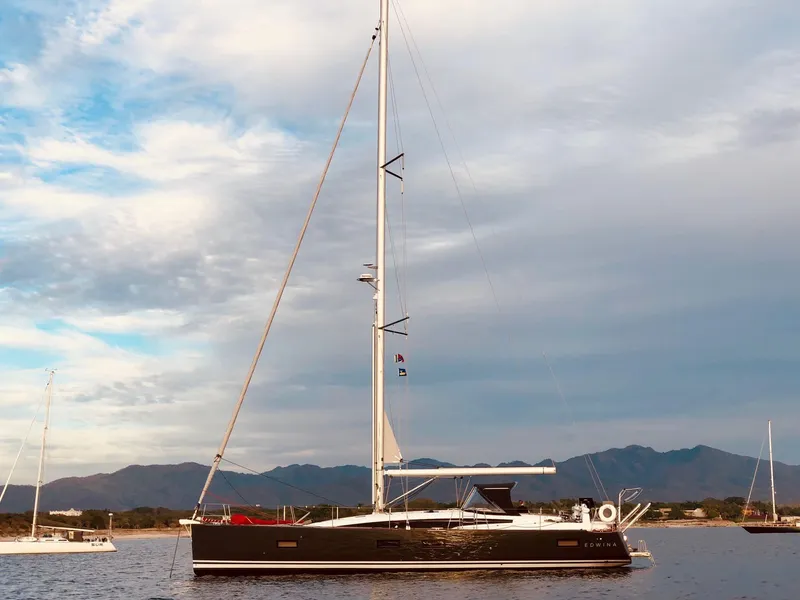 Slide: The Image of 2018 Jeanneau 54 yacht sailing on calm waters with mountainous backdrop. - 8