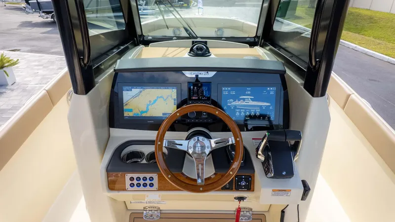 Slide: The Image of 2025 Chris-Craft Catalina 28 helm with modern navigation displays and wooden steering wheel. - 19