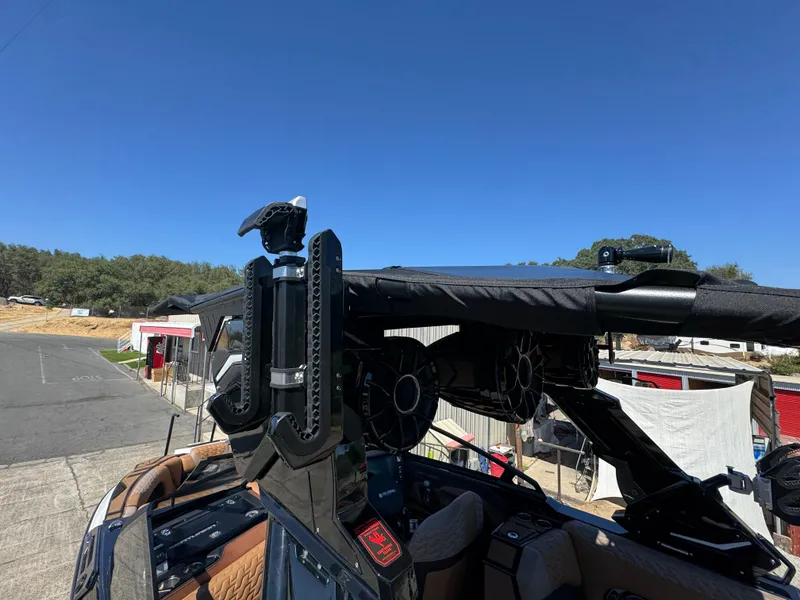 Slide: The Image of 2025 Centurion RI 245 boat with advanced wakeboard tower and speakers, parked outdoors. - 45