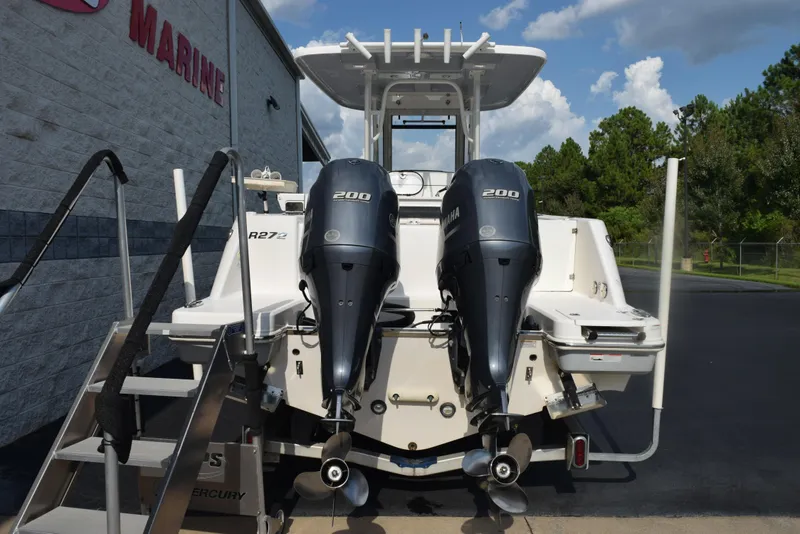 Slide: The Image of 2019 Robalo R272 Center Console boat with dual Yamaha 200 engines, parked near a marine store. - 5