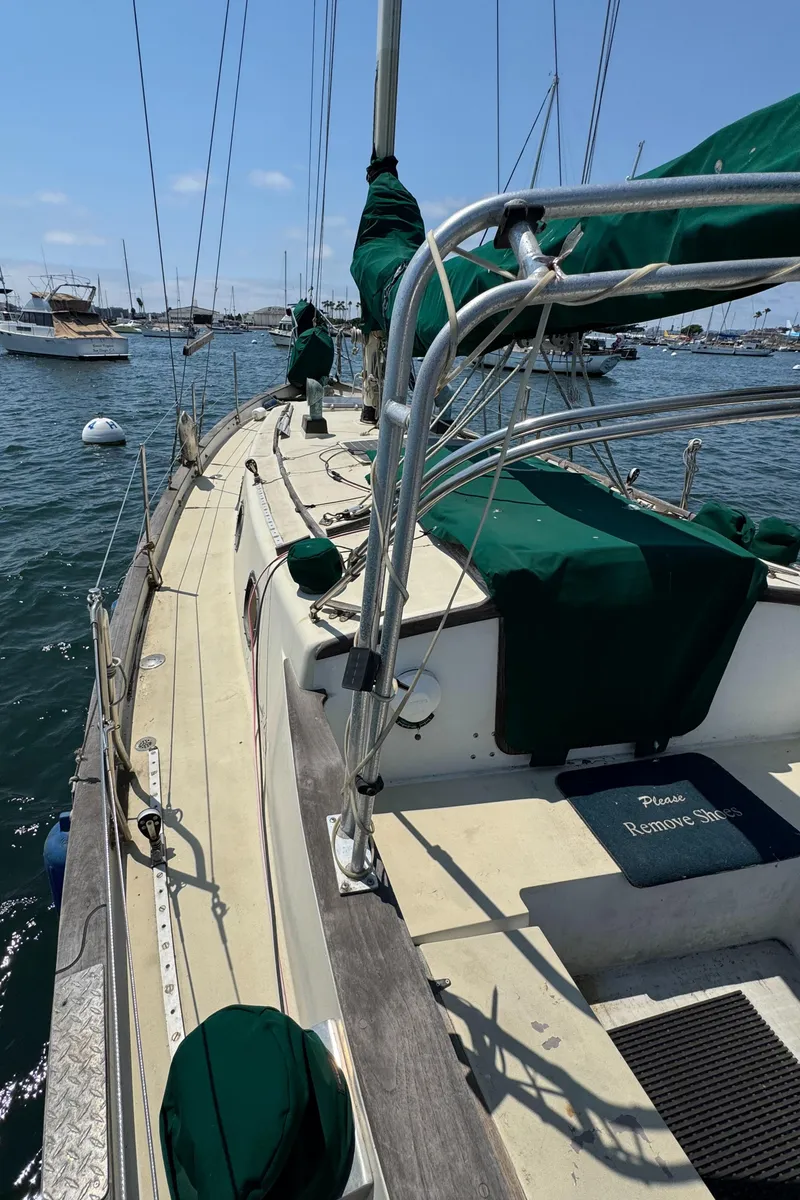 Slide: The Image of 1985 Bluewater Ingrid 38 sailboat deck with green covers, moored in a marina. - 14