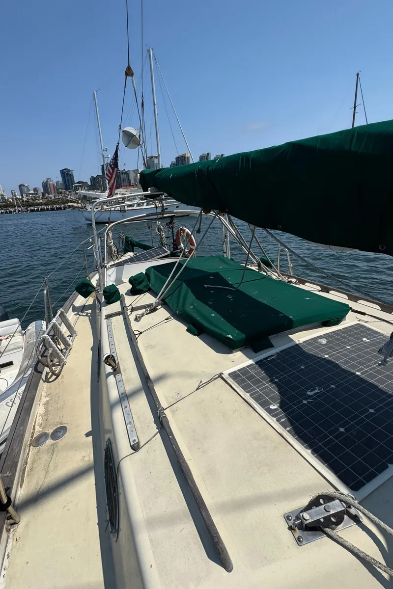 Slide: The Image of 1985 Bluewater Ingrid 38 sailboat docked, featuring green covers and solar panels. - 15