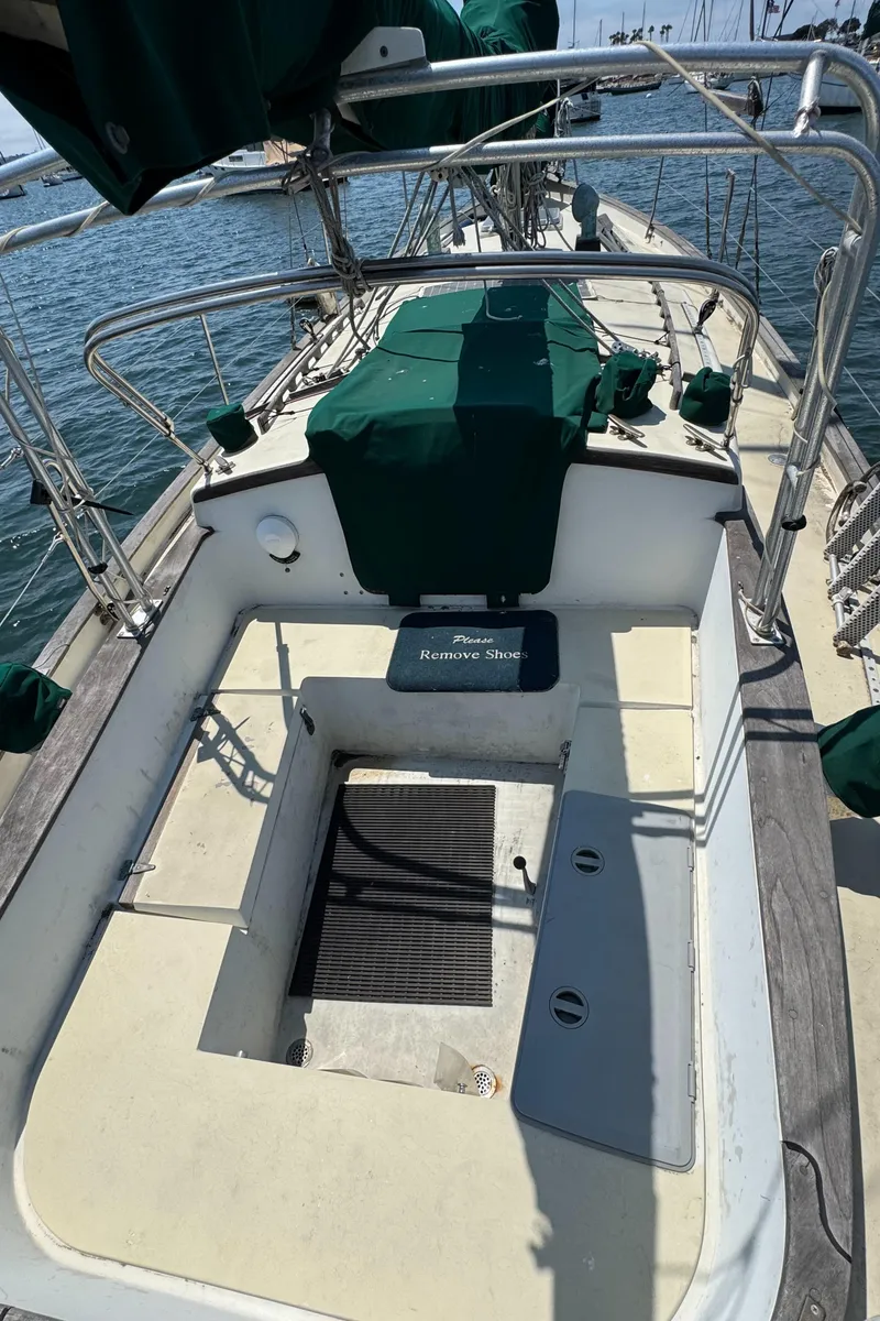 Slide: The Image of 1985 Bluewater Ingrid 38 sailboat cockpit with green covers and "Please Remove Shoes" sign. - 16
