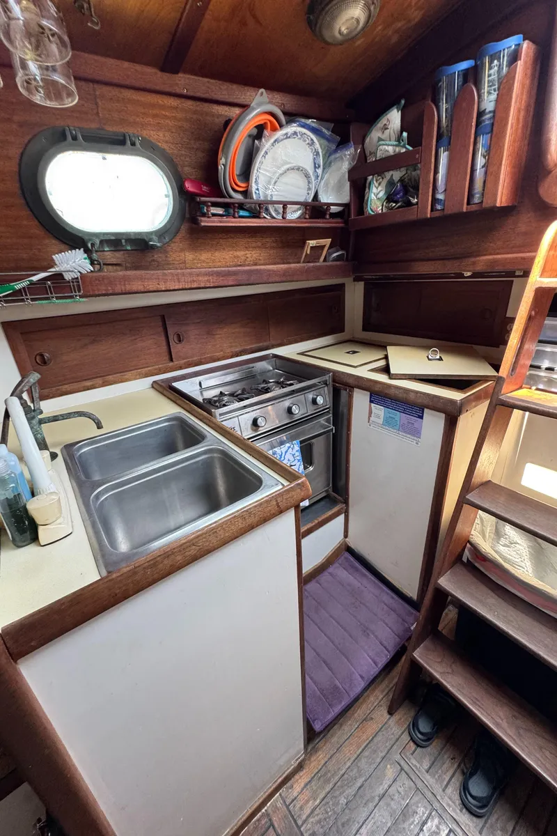 Slide: The Image of 1985 Bluewater Ingrid 38 yacht kitchen with wooden cabinetry, dual sink, and compact stove. - 21