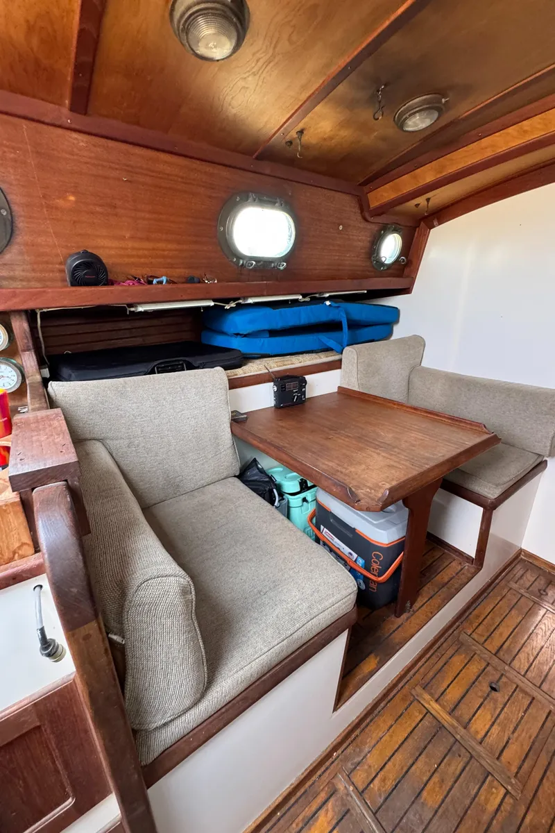Slide: The Image of Cozy interior of 1985 Bluewater Ingrid 38 sailboat with wooden table and cushioned seating. - 35