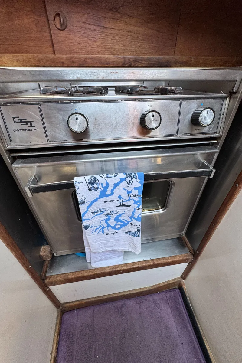 Slide: The Image of 1985 Bluewater Ingrid 38 boat kitchen with vintage gas oven and nautical-themed towel. - 36