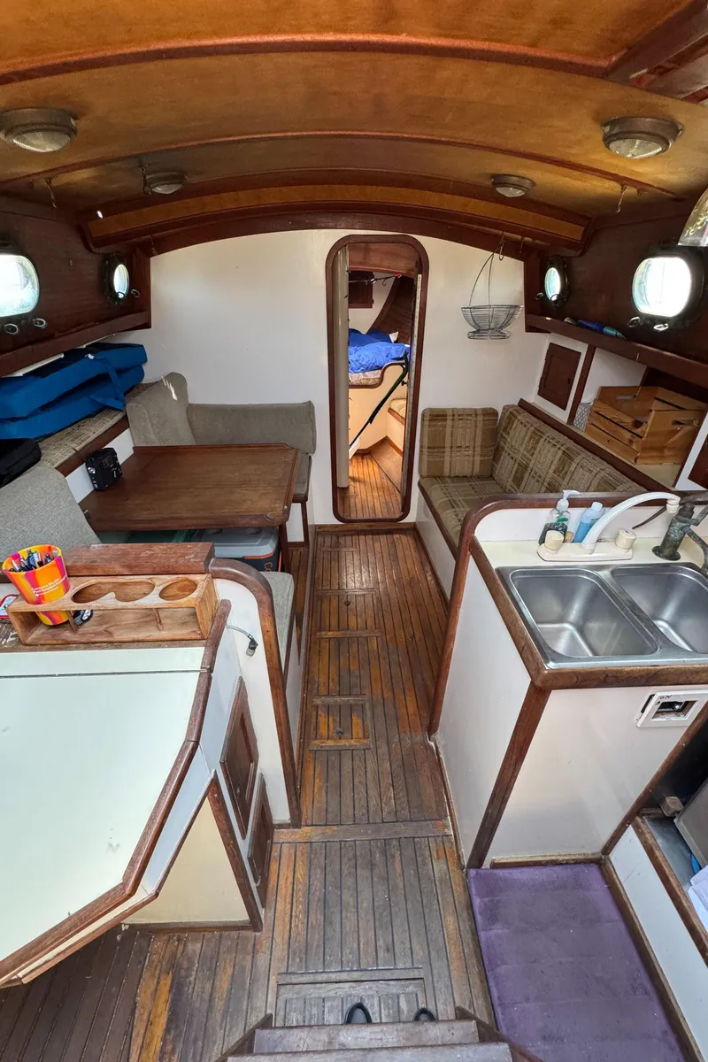Slide: The Image of Interior of 1985 Bluewater Ingrid 38 sailboat with wooden furnishings and compact kitchen area. - 37
