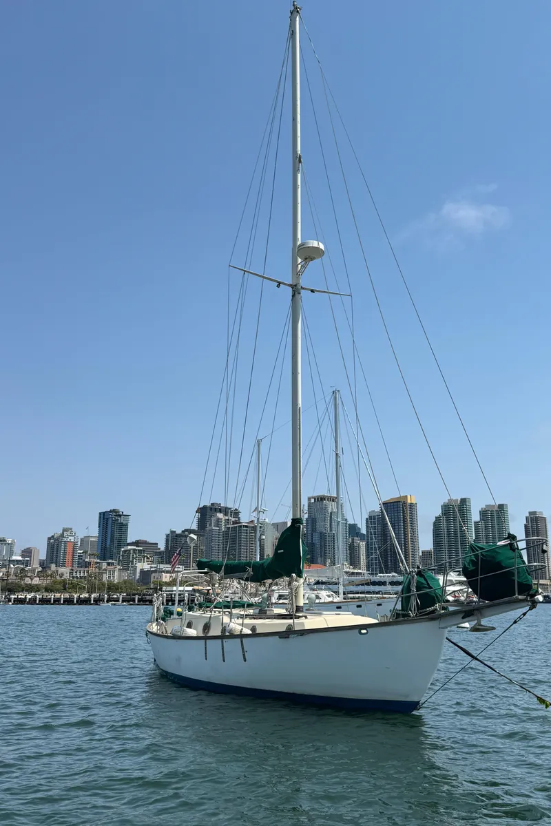 Slide: The Image of Sailboat Bluewater Ingrid 38, 1985, docked in urban marina with city skyline backdrop. - 4