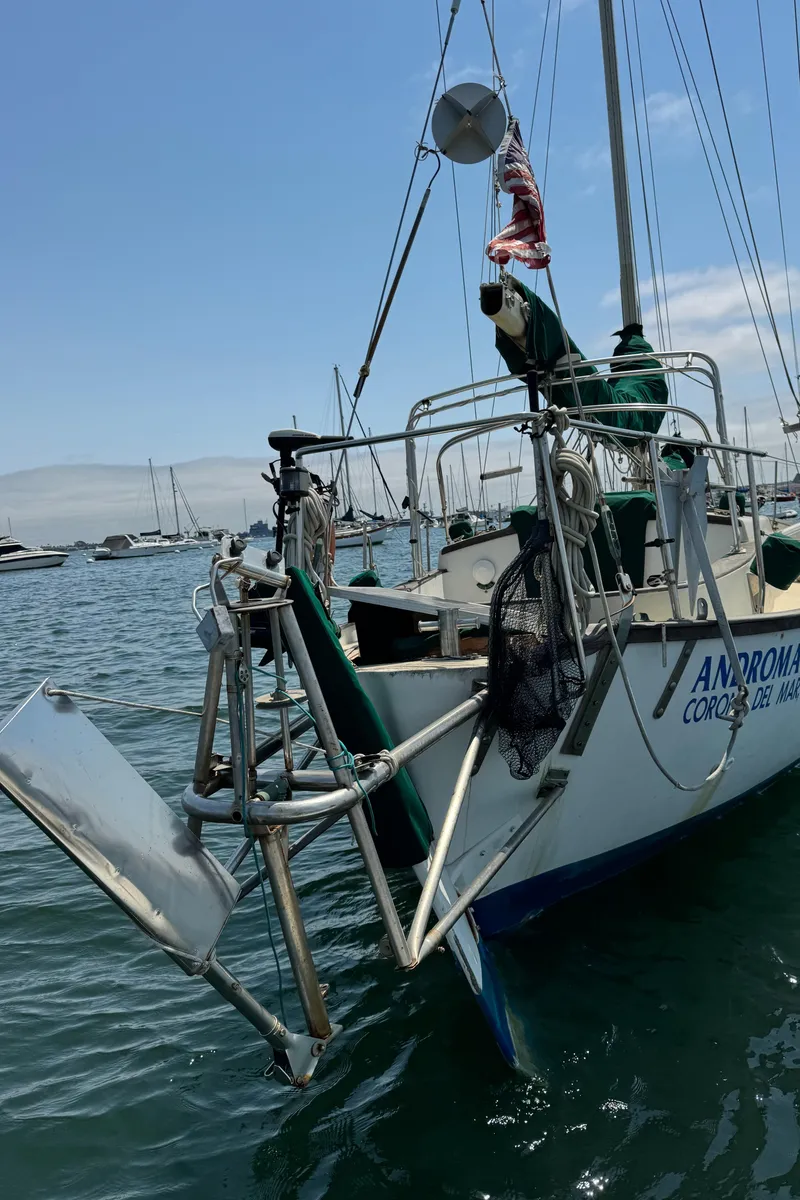 Slide: The Image of 1985 Bluewater Ingrid 38 sailboat docked in marina, featuring American flag and clear sky. - 8