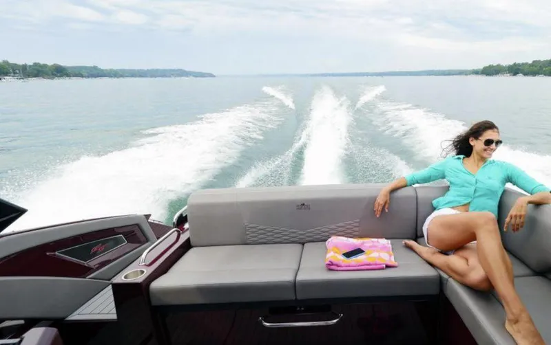 Slide: The Image of 2019 Cruisers Yachts 338 IO on water, woman relaxing on deck, scenic lake view. - 3