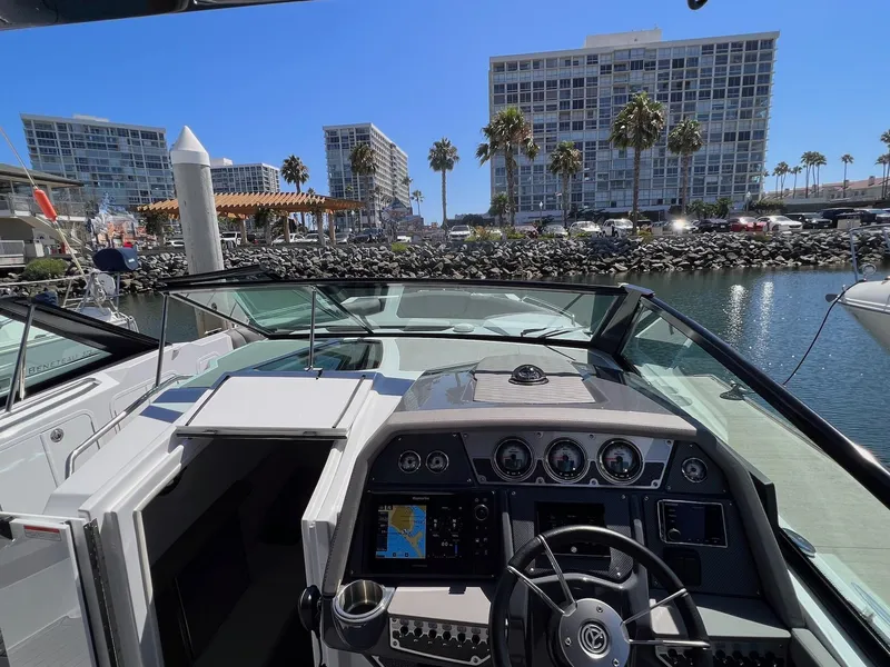Slide: The Image of 2019 Cruisers Yachts 338 IO boat dashboard with marina view and modern buildings. - 9