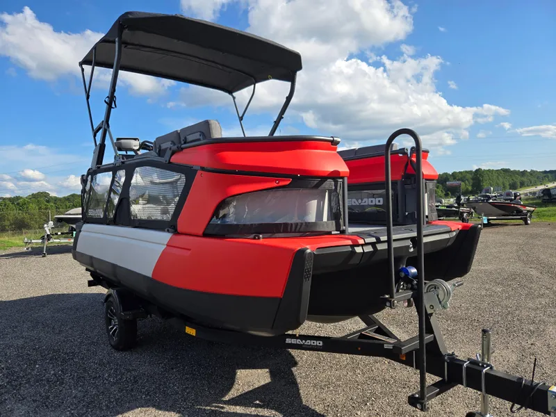 Slide: The Image of 2023 Sea-Doo Switch Cruise 18 pontoon boat on trailer under blue sky. - 2
