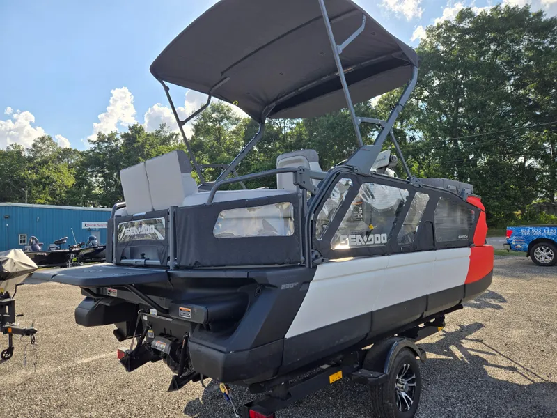 Slide: The Image of 2023 Sea-Doo Switch Cruise 18 pontoon boat with canopy, parked outdoors on a sunny day. - 4