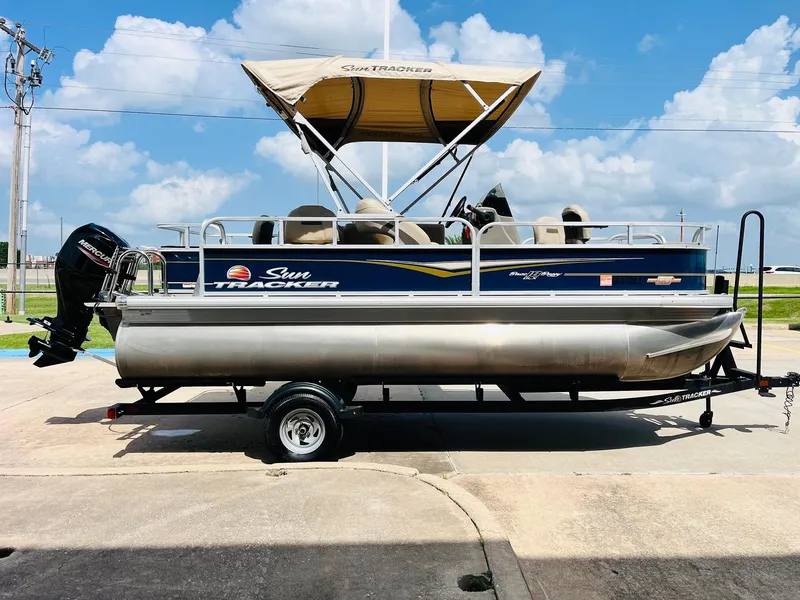 Slide: The Image of 2023 Sun Tracker Bass Buggy 18 DLX pontoon boat on trailer, under blue sky. - 3