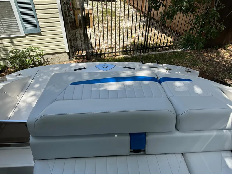 Slide: The Image of 2008 Regal 2250 Cuddy boat with white and blue seating, parked near a fence. - 15