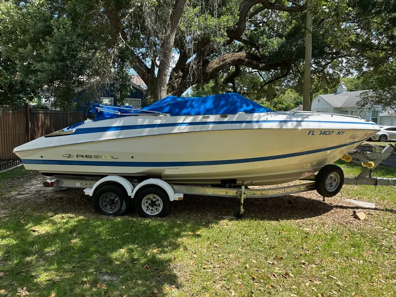 Slide: The Image of 2008 Regal 2250 Cuddy boat on trailer, covered with blue tarp, parked outdoors. - 3