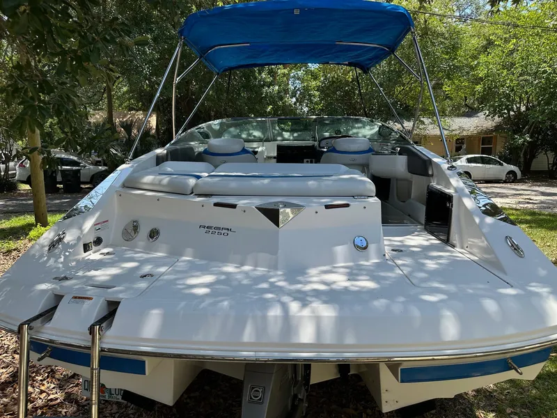 Slide: The Image of 2008 Regal 2250 Cuddy boat with blue canopy, parked outdoors under trees. - 9