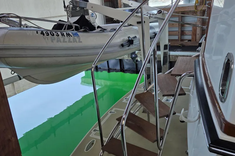 Slide: The Image of 1985 Chris-Craft 500 Constellation Motor Yacht with dinghy and wooden steps in a marina. - 9