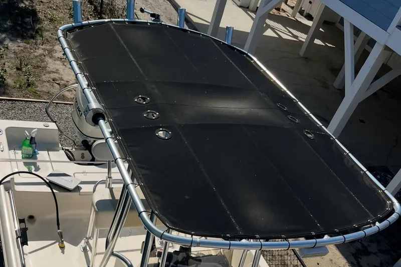 Slide: The Image of 2020 Bulls Bay 2000 boat with black T-top cover, docked outdoors. - 12