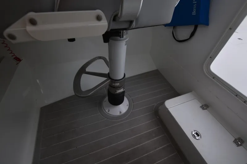 Slide: The Image of Interior of a 2025 Parker 2420 boat, featuring a steering wheel and storage compartment. - 16