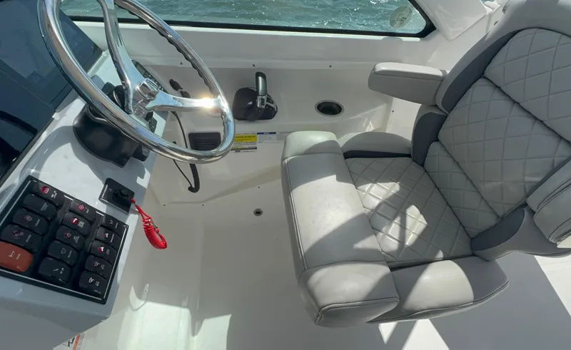 Slide: The Image of 2023 Pursuit DC 246 Dual Console interior with steering wheel and cushioned seat. - 17