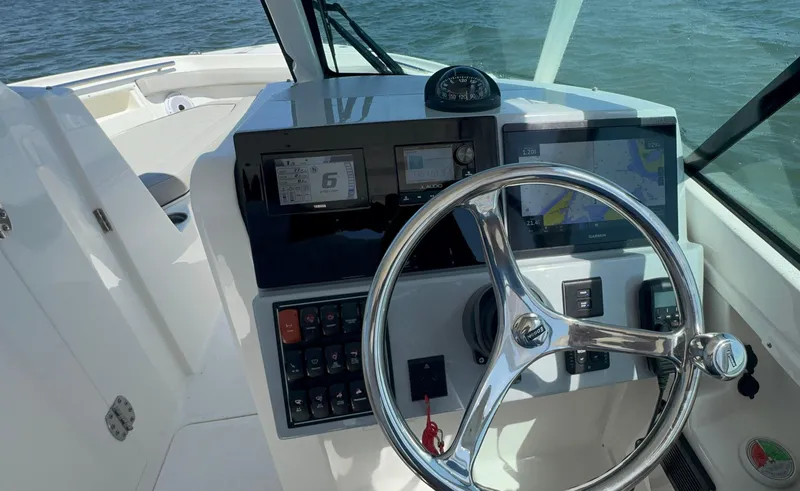 Slide: The Image of 2023 Pursuit DC 246 Dual Console boat dashboard with steering wheel and navigation displays. - 18