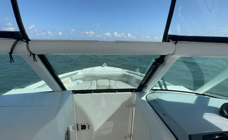 Slide: The Image of 2023 Pursuit DC 246 Dual Console boat on open water, viewed from cockpit. - 20