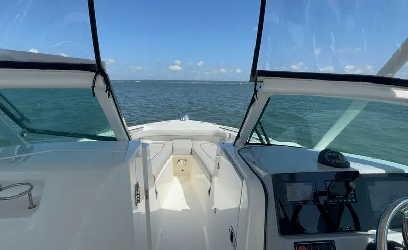 Slide: The Image of 2023 Pursuit DC 246 Dual Console boat on open water, clear sky, modern dashboard. - 21