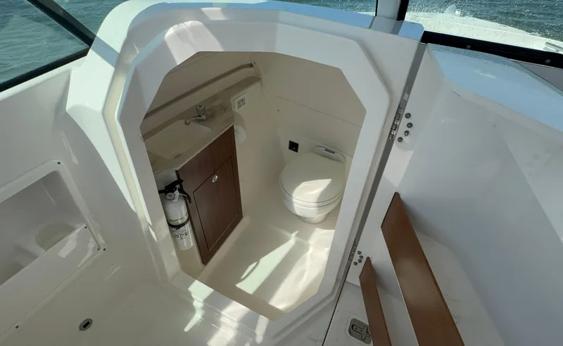 Slide: The Image of 2023 Pursuit DC 246 Dual Console boat interior with compact bathroom and sink. - 24