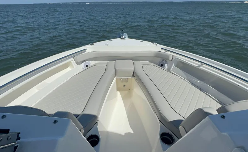 Slide: The Image of 2023 Pursuit DC 246 Dual Console boat interior with cushioned seating on open water. - 25