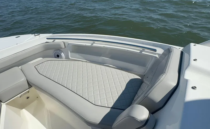 Slide: The Image of 2023 Pursuit DC 246 Dual Console boat with cushioned seating, on calm water. - 26