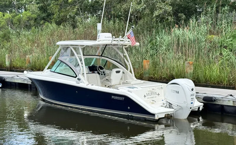 Slide: The Image of 2023 Pursuit DC 246 Dual Console boat docked by lush greenery. - 3