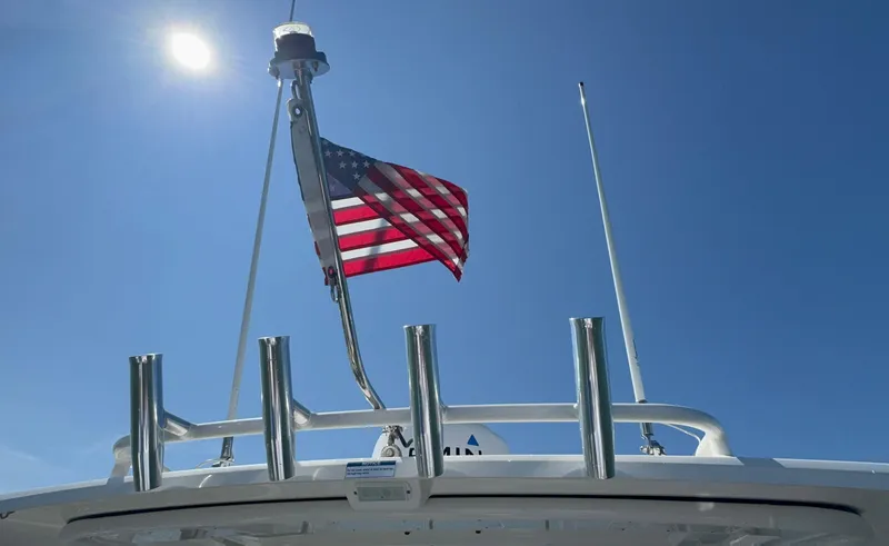 Slide: The Image of 2023 Pursuit DC 246 Dual Console boat with American flag under clear blue sky. - 31