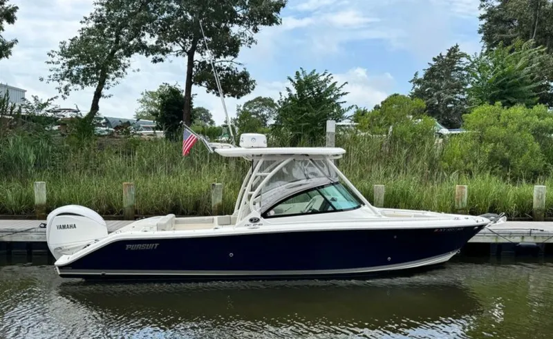Slide: The Image of 2023 Pursuit DC 246 Dual Console boat docked by lush greenery. - 4