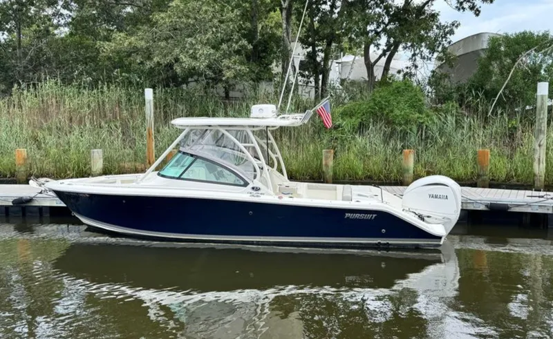 Slide: The Image of 2023 Pursuit DC 246 Dual Console boat docked by lush greenery. - 5