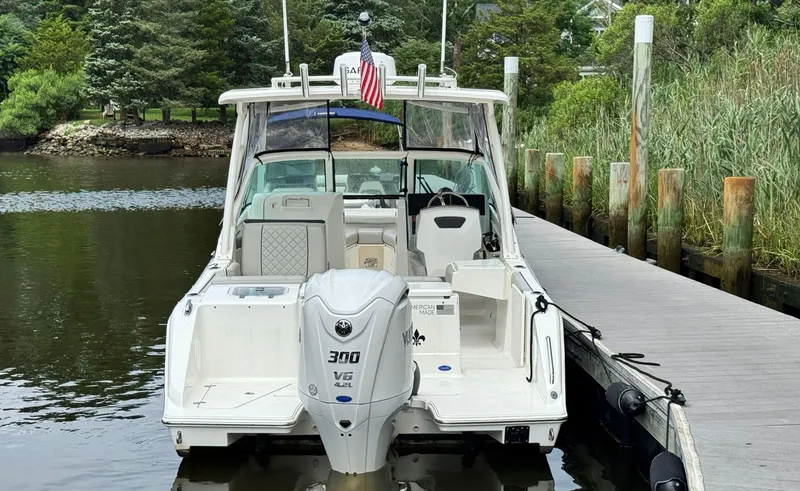 Slide: The Image of 2023 Pursuit DC 246 Dual Console boat docked by a wooden pier, featuring a powerful outboard motor. - 6