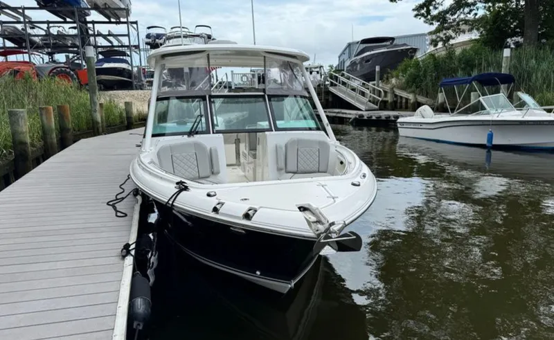 Slide: The Image of 2023 Pursuit DC 246 Dual Console boat docked at marina, surrounded by water and other boats. - 7