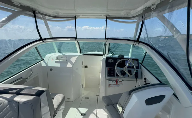 Slide: The Image of 2023 Pursuit DC 246 Dual Console boat interior with steering wheel and seating on open water. - 8