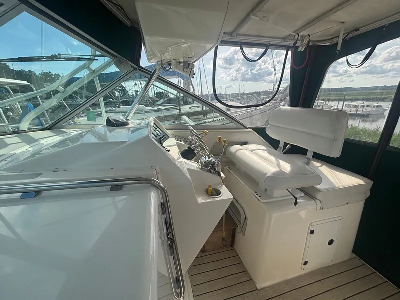 Slide: The Image of 1998 Wellcraft 330 Coastal boat cockpit with steering wheel and seating, docked at marina. - 14