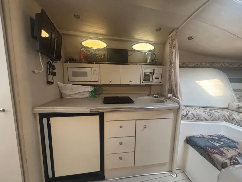 Slide: The Image of 1998 Wellcraft 330 Coastal interior with kitchenette, microwave, and cozy seating area. - 19