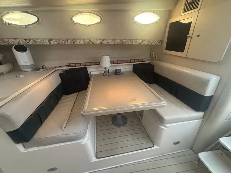 Slide: The Image of 1998 Wellcraft 330 Coastal cabin interior with dining area, cushioned seating, and porthole windows. - 20