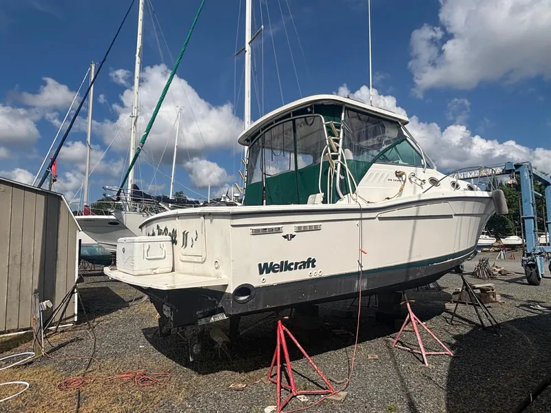 Slide: The Image of 1998 Wellcraft 330 Coastal boat on stands, under a partly cloudy sky. - 3
