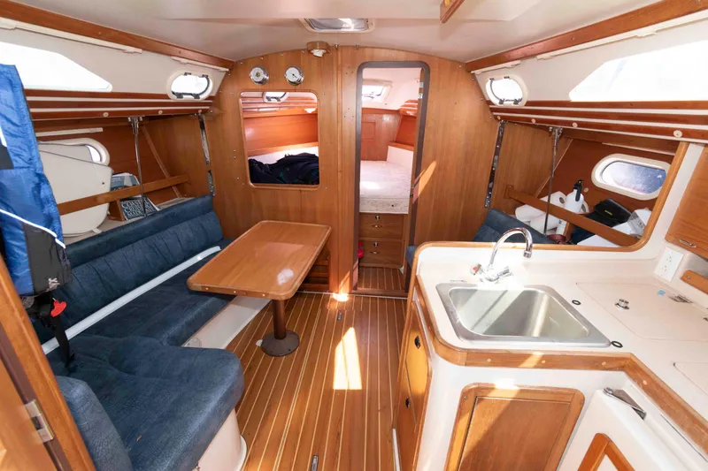 Slide: The Image of Interior of a 2003 Catalina 310 sailboat featuring a cozy cabin with seating and kitchenette. - 10