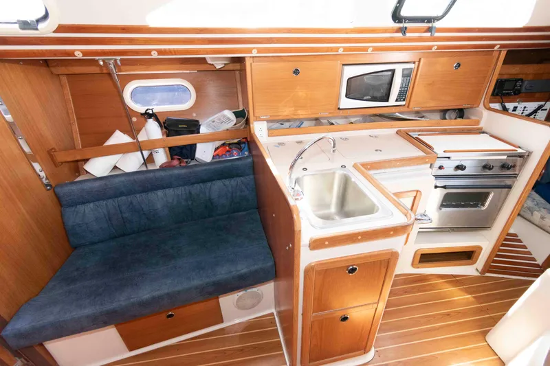 Slide: The Image of Interior of a 2003 Catalina 310 sailboat featuring a compact kitchen and seating area. - 12