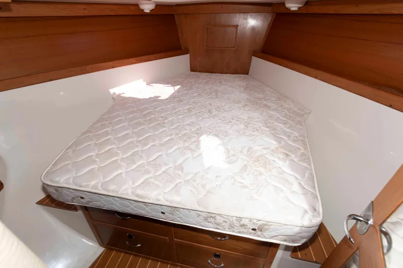 Slide: The Image of 2003 Catalina 310 yacht cabin with a comfortable mattress and wooden storage drawers. - 15