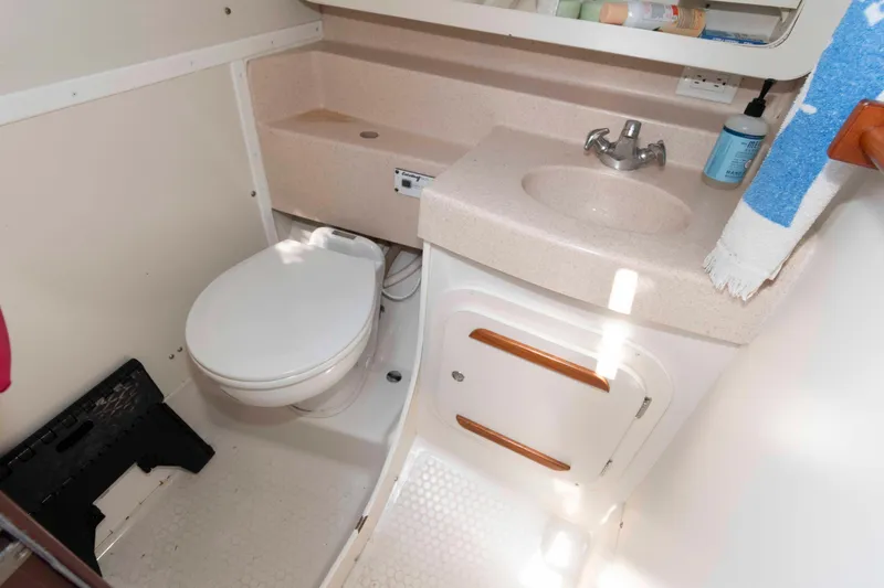 Slide: The Image of 2003 Catalina 310 boat bathroom with toilet, sink, and storage cabinet. - 16