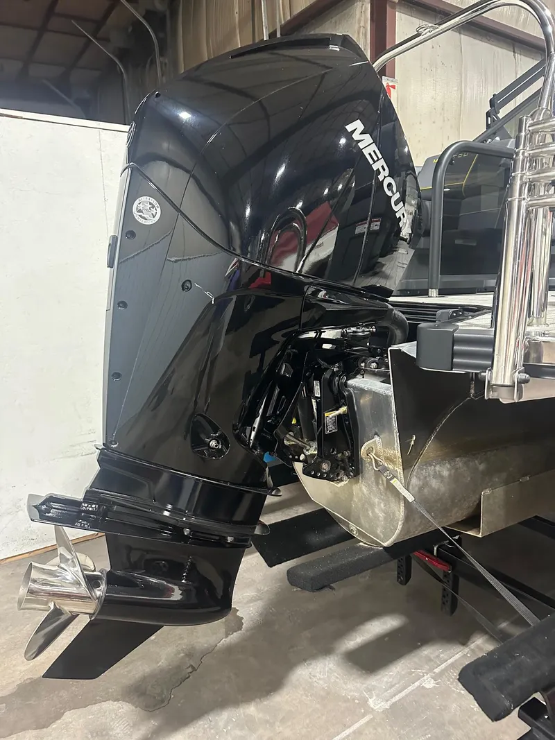 Slide: The Image of 2023 Manitou Explore 24 Navigator with Mercury outboard motor in a garage setting. - 13