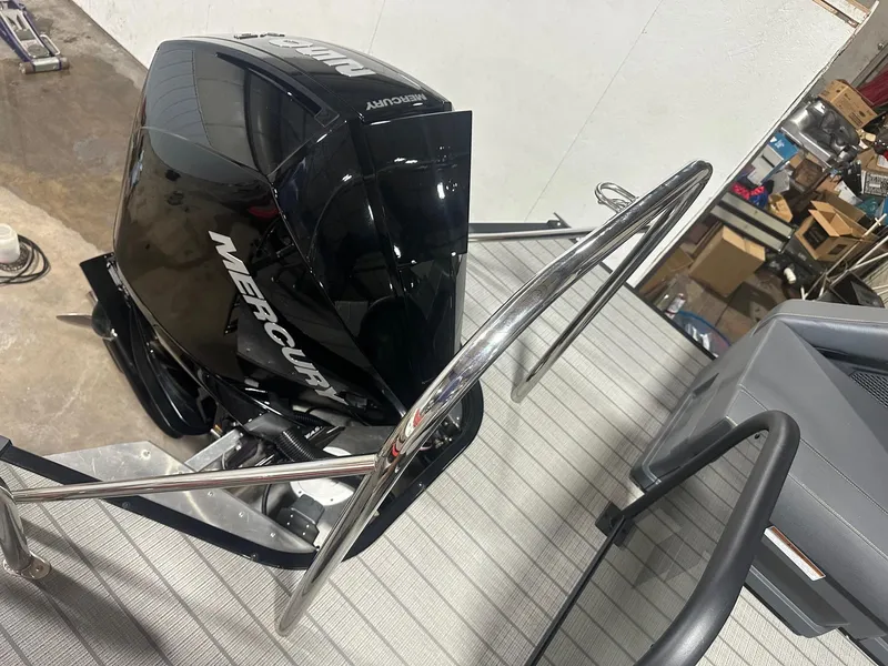 Slide: The Image of 2023 Manitou Explore 24 Navigator with Mercury engine and trifold bench, in a workshop setting. - 22